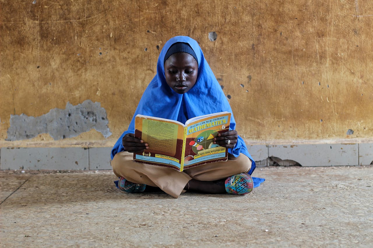 Young Girl Sitting and Reading a Textbook